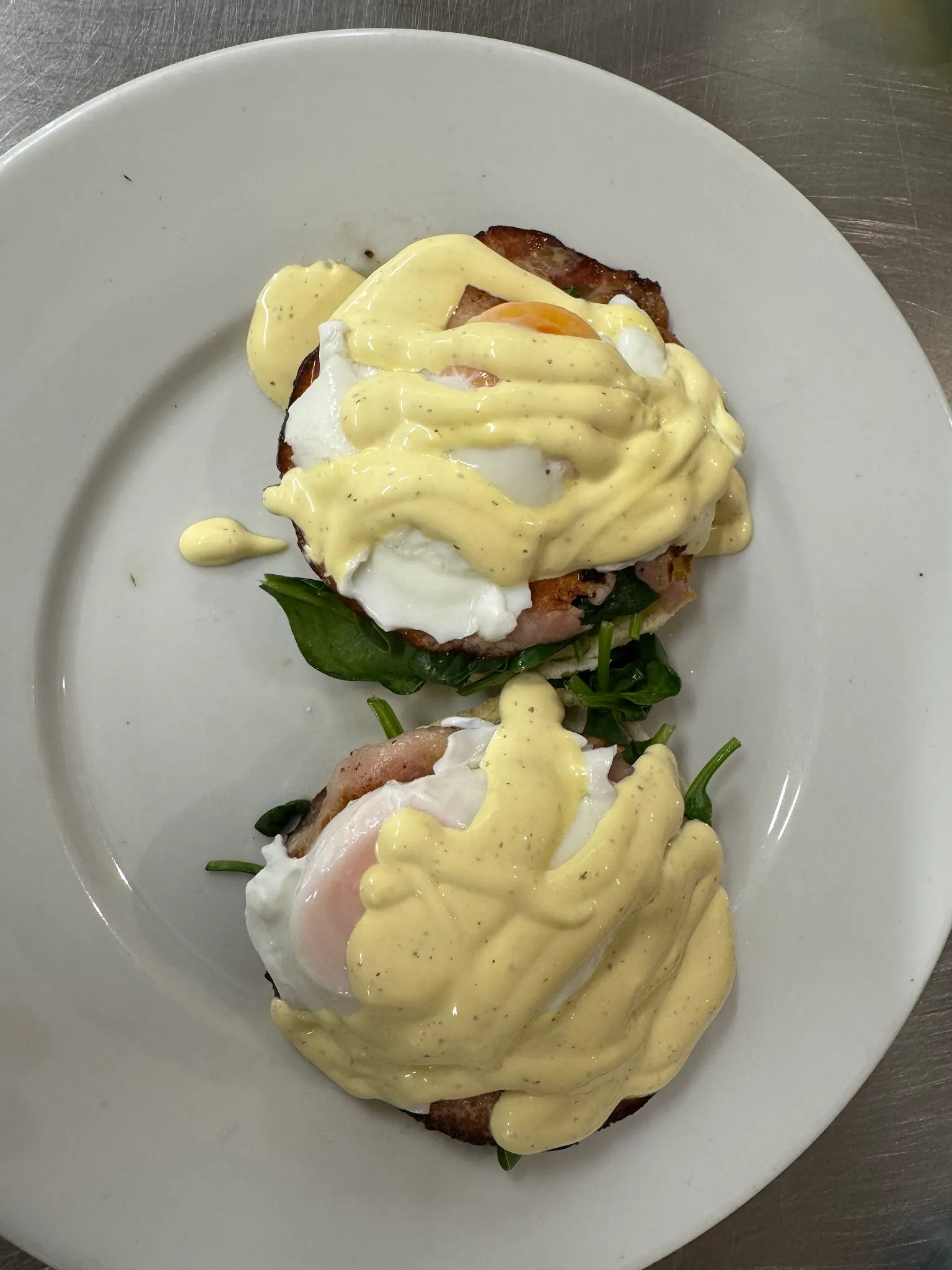 Two eggs Benedict servings topped with hollandaise sauce