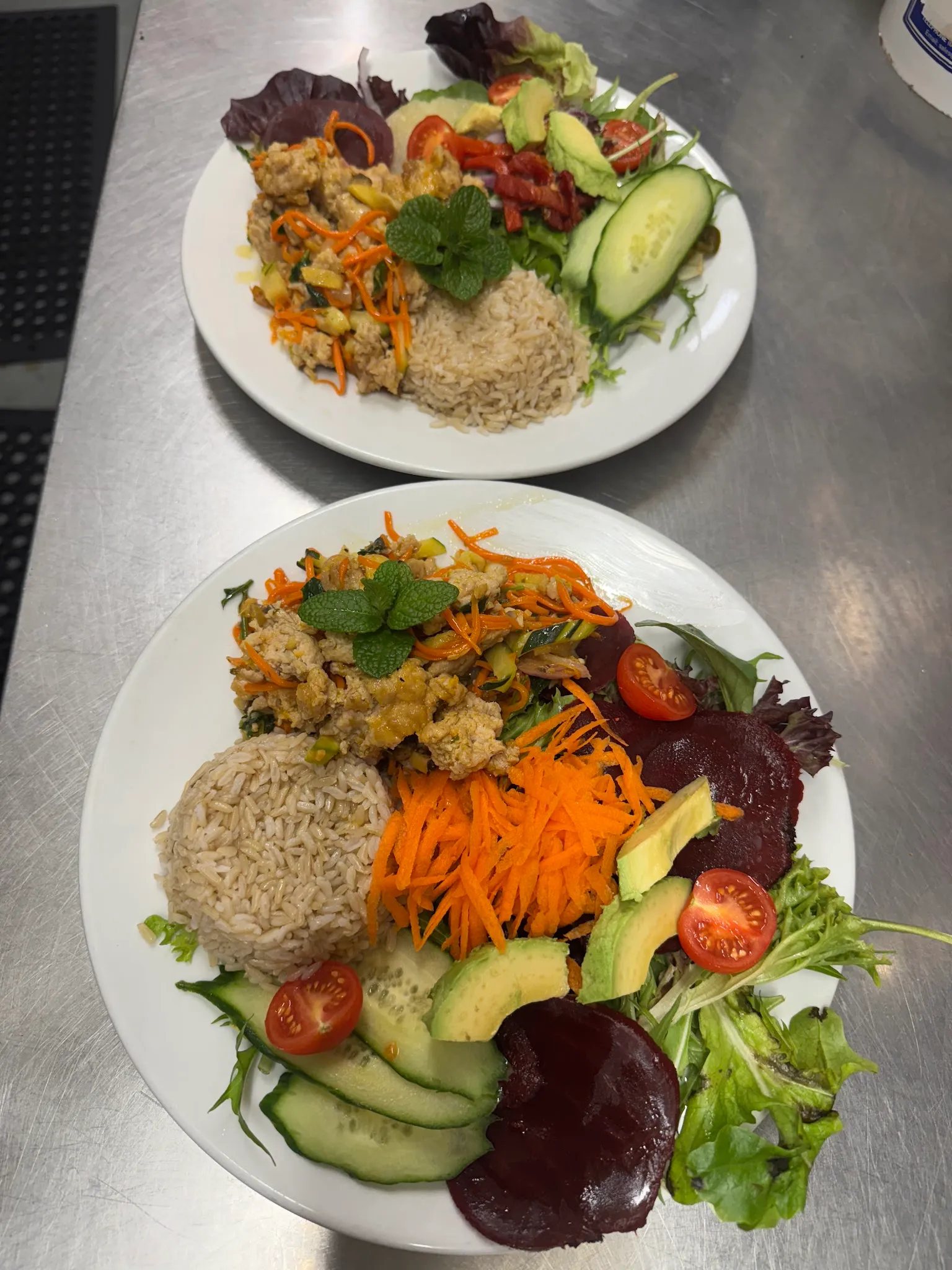 Two plates of mince curry with rice and fresh garden salad