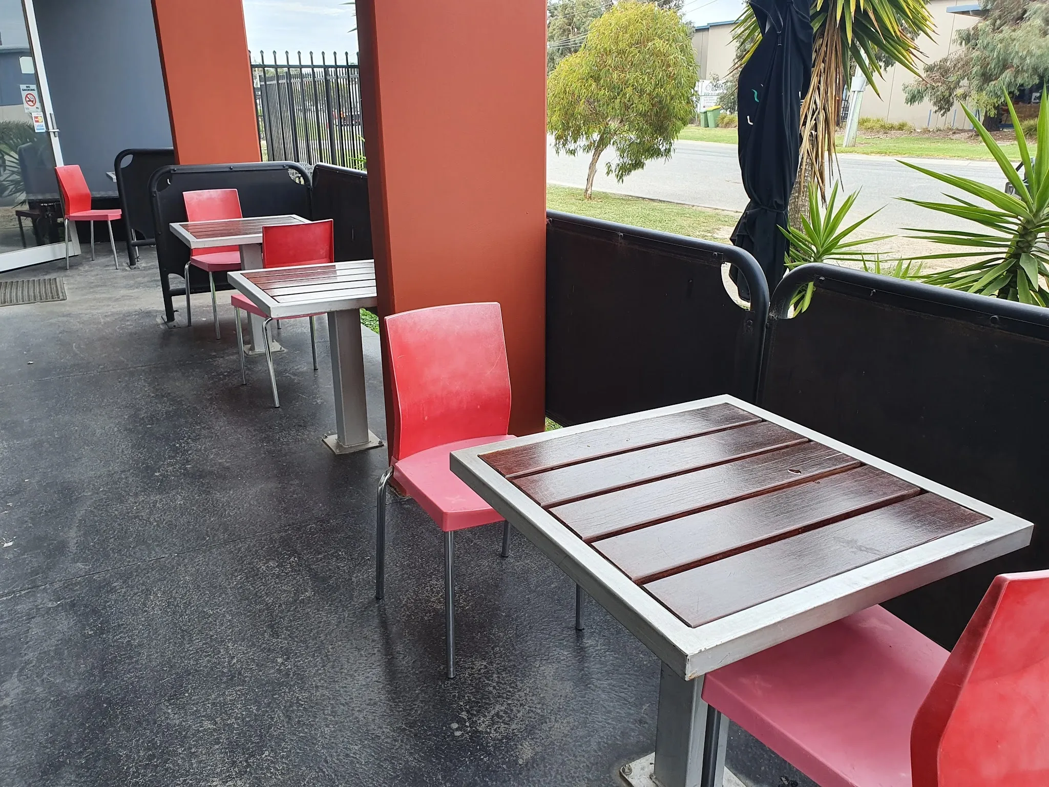 Outdoor covered seating area with red chairs and tables