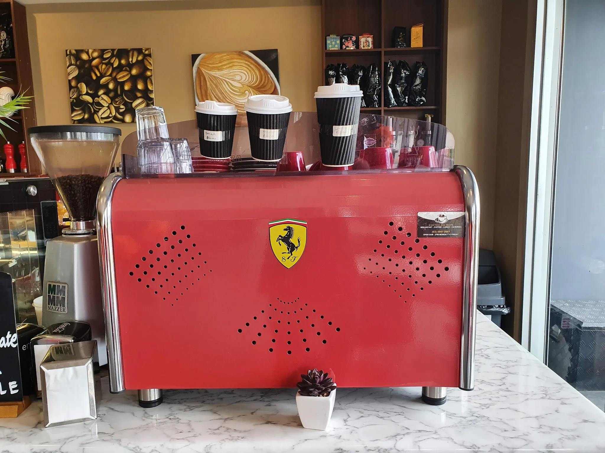 Red espresso machine with takeaway coffee cups and price labels